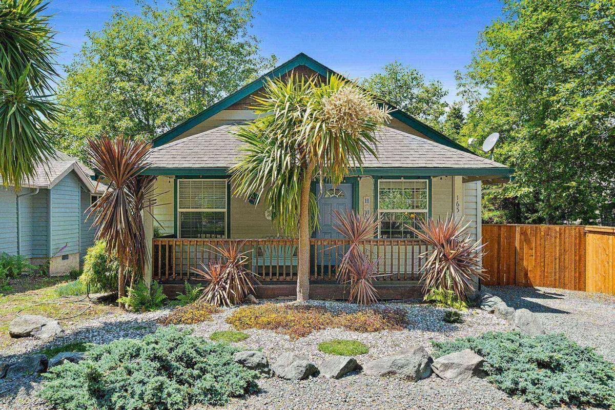 A vibrant and welcoming front porch bordered by palm trees and colorful shrubs, creating an inviting atmosphere that beckons guests and their pets to explore the area or relax outside. The lush landscaping and open porch set the scene for family and pet-friendly gatherings.