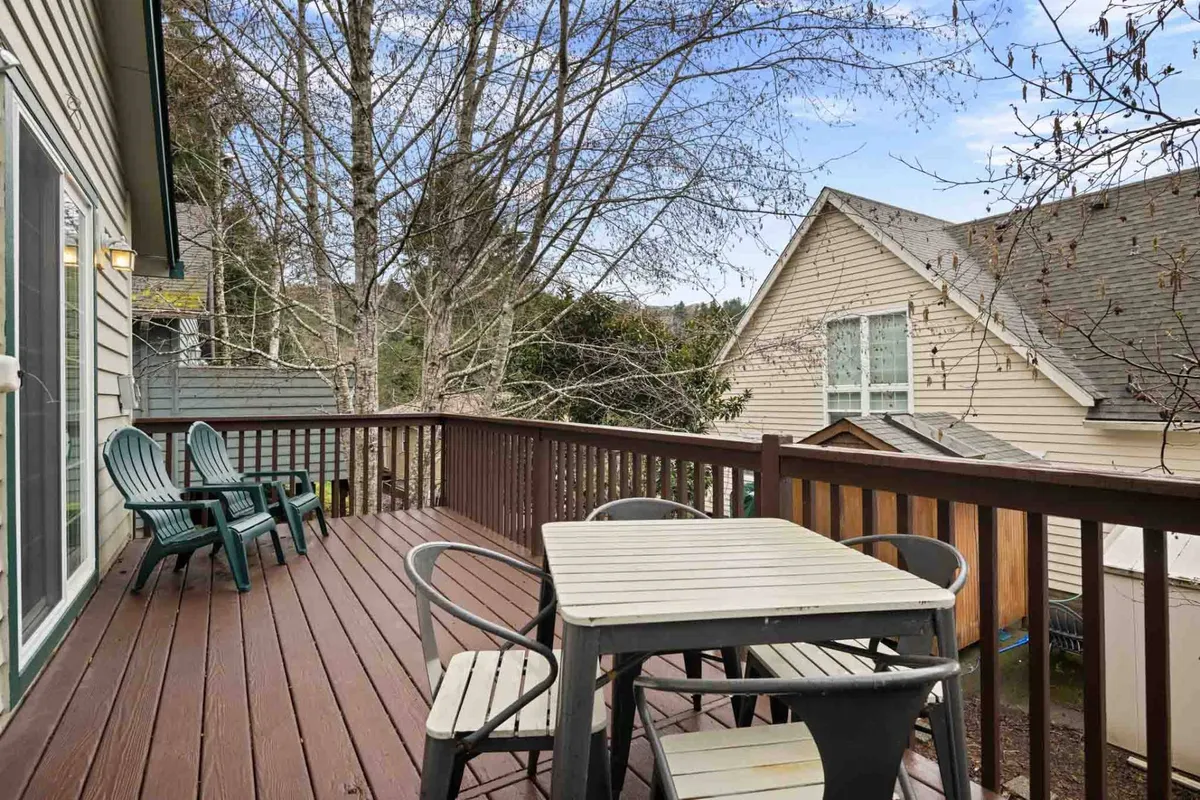 A tranquil exterior shot featuring a cozy deck surrounded by trees, with comfortable outdoor furniture ideal for relaxing or socializing. The deck provides a private space to unwind after a day of adventure and connects seamlessly to the outdoors.